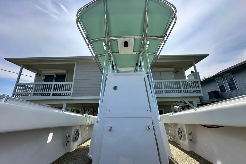 Slide: The Image of 2013 Contender 25 Tournament boat with T-top, parked near a house under a clear sky. - 45