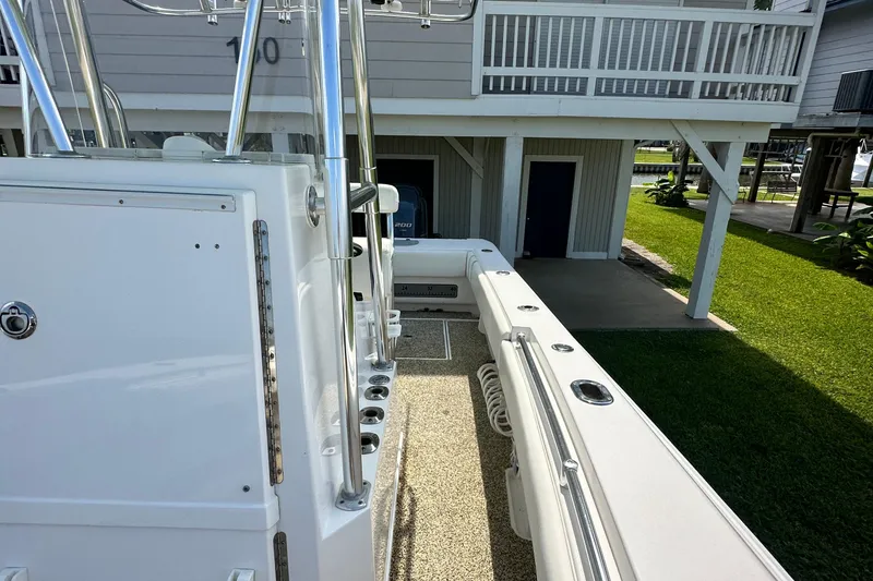 Slide: The Image of 2013 Contender 25 Tournament boat, white deck, docked near a house with green lawn. - 48