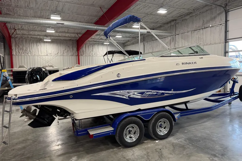 Slide: The Image of 2006 Rinker 246 boat in a warehouse, blue and white design on trailer. - 2