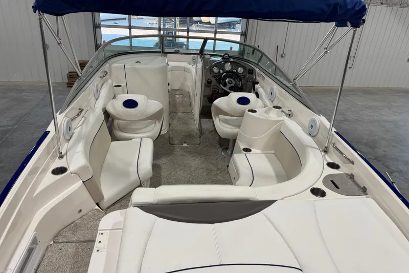 Slide: The Image of 2006 Rinker 246 boat interior with white seating and blue accents in a spacious cabin. - 21