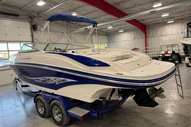 Slide: The Image of 2006 Rinker 246 boat with blue and white design on a trailer in a garage. - 3