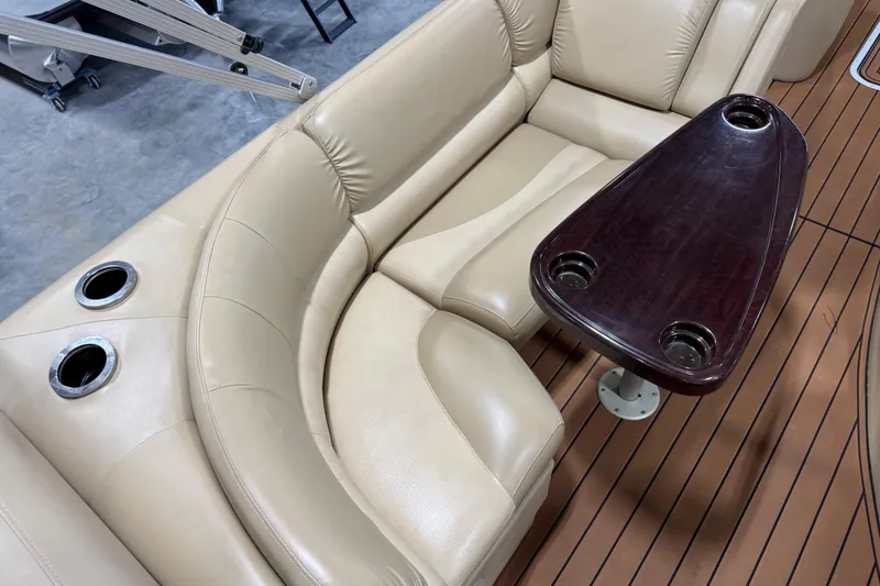 Slide: The Image of 2011 Bennington 2575 RCW I/O boat interior with beige seating and wooden table. - 10