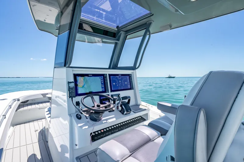 Slide: The Image of 2022 Costa Custom Boats 264 helm with dual screens, steering wheel, and ocean view. - 22