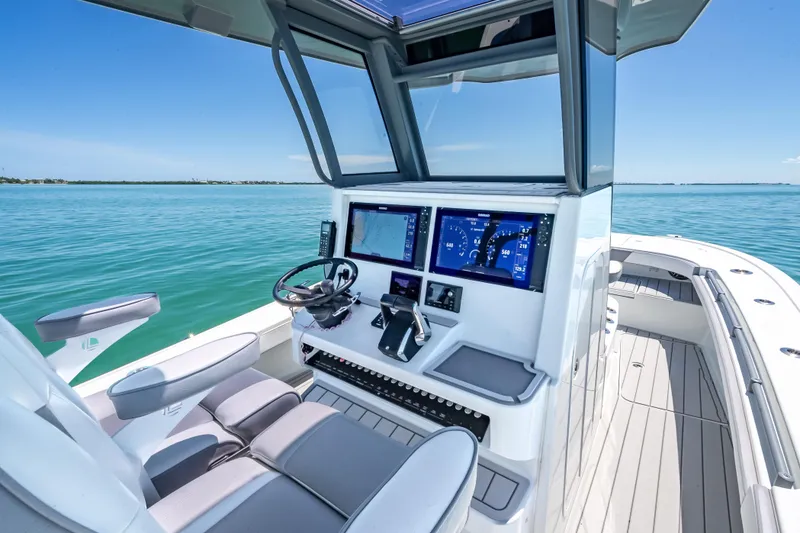 Slide: The Image of 2022 Costa Custom Boats 264 helm with modern controls on calm blue water. - 24