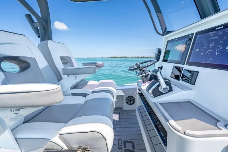 Slide: The Image of 2022 Costa Custom Boats 264 cockpit with modern controls and seating on a sunny day. - 27