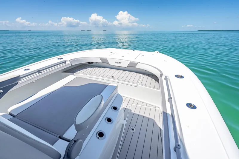 Slide: The Image of 2022 Costa Custom Boats 264 on serene blue water, showcasing spacious deck and seating. - 32