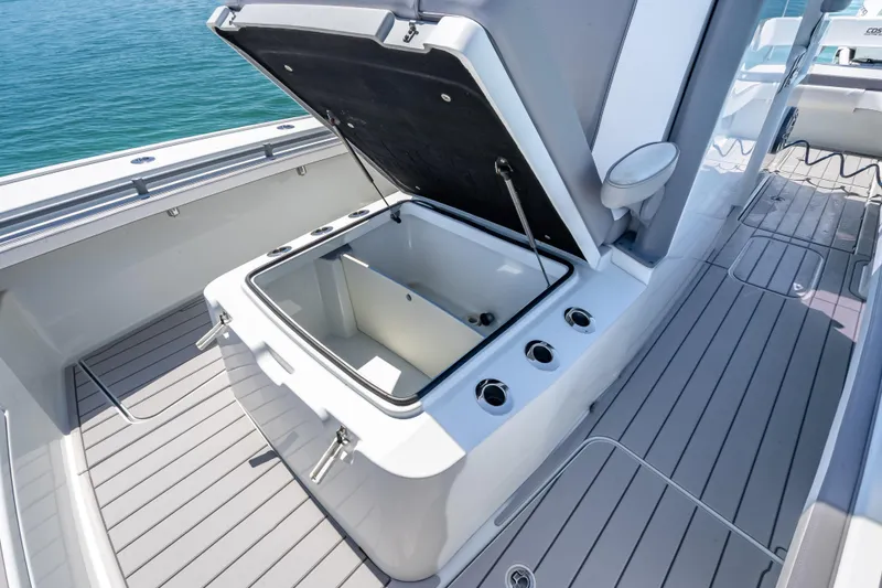 Slide: The Image of 2022 Costa Custom Boats 264 with open storage compartment on deck, docked on water. - 34