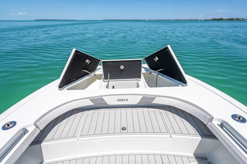 Slide: The Image of 2022 Costa Custom Boats 264 on calm blue water, open storage compartments. - 38