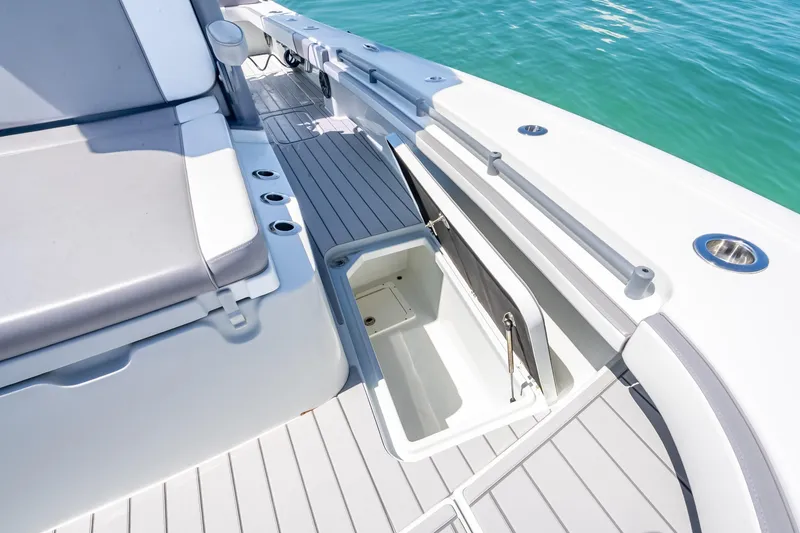 Slide: The Image of 2022 Costa Custom Boats 264 deck with open storage compartment, gray seating, and ocean view. - 39