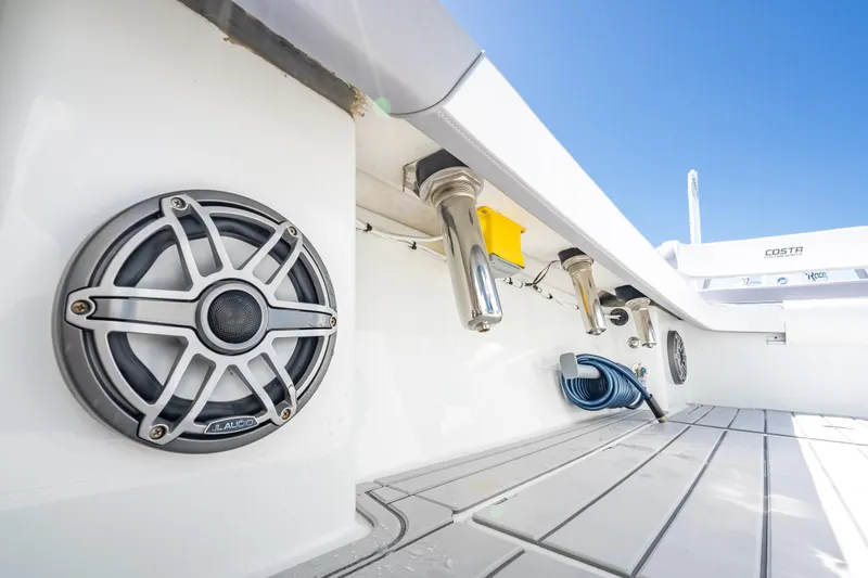Slide: The Image of 2022 Costa Custom Boats 264 deck with speakers and rod holders under clear blue sky. - 54