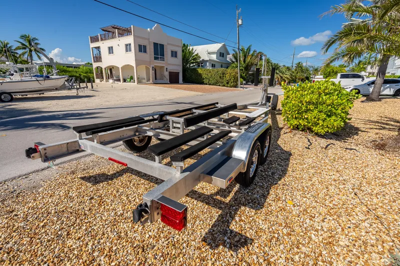 Slide: The Image of Trailer for 2022 Costa Custom Boats 264, parked on gravel near palm trees and houses. - 64