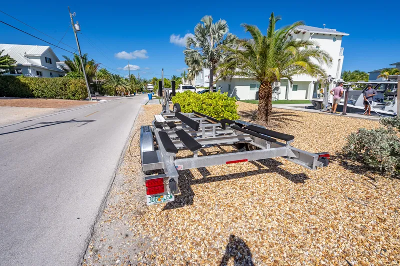 Slide: The Image of Trailer for 2022 Costa Custom Boats 264 parked on gravel near palm trees. - 65