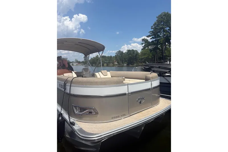 Slide: The Image of 2023 Tahoe Pontoon Cascade Rear Lounger on a sunny lake with trees in the background. - 1