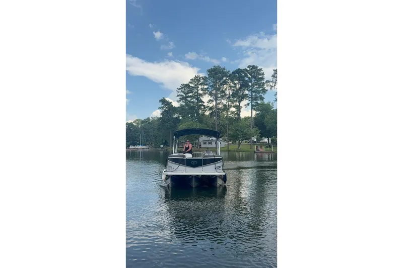 Slide: The Image of 2023 Tahoe Pontoon Sport LTZ Quad Lounger on a serene lake with trees in the background. - 4