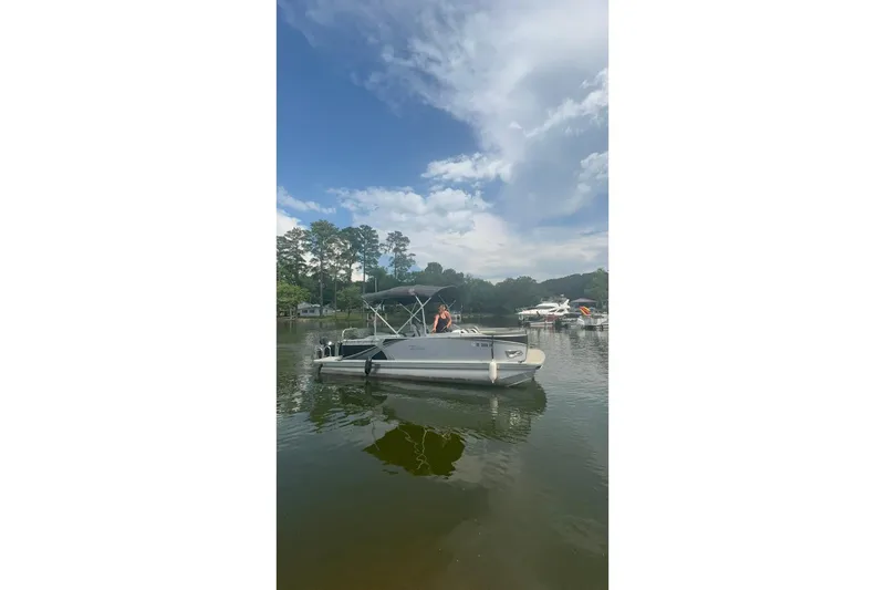 Slide: The Image of 2023 Tahoe Pontoon Sport LTZ Quad Lounger on a serene lake under a blue sky. - 8
