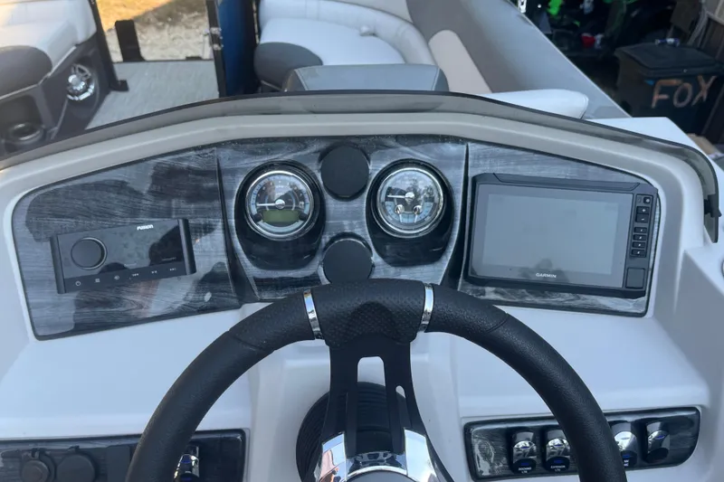 Slide: The Image of 2023 Avalon LSZ 2585 QL boat dashboard with steering wheel, gauges, and Garmin display. - 13