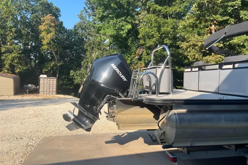 Slide: The Image of 2023 Avalon LSZ 2585 QL pontoon boat with Mercury outboard motor, parked outdoors. - 4