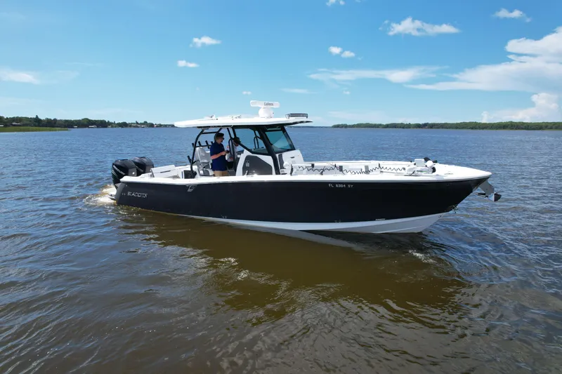 Slide: The Image of 2021 Blackfin 332 CC boat cruising on a calm lake under a clear blue sky. - 13