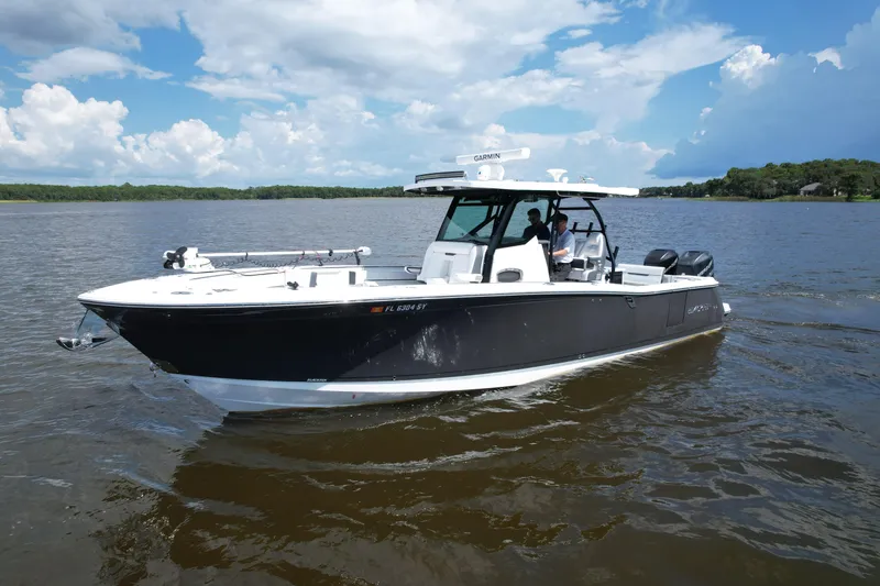 Slide: The Image of 2021 Blackfin 332 CC boat cruising on a calm lake under a partly cloudy sky. - 16