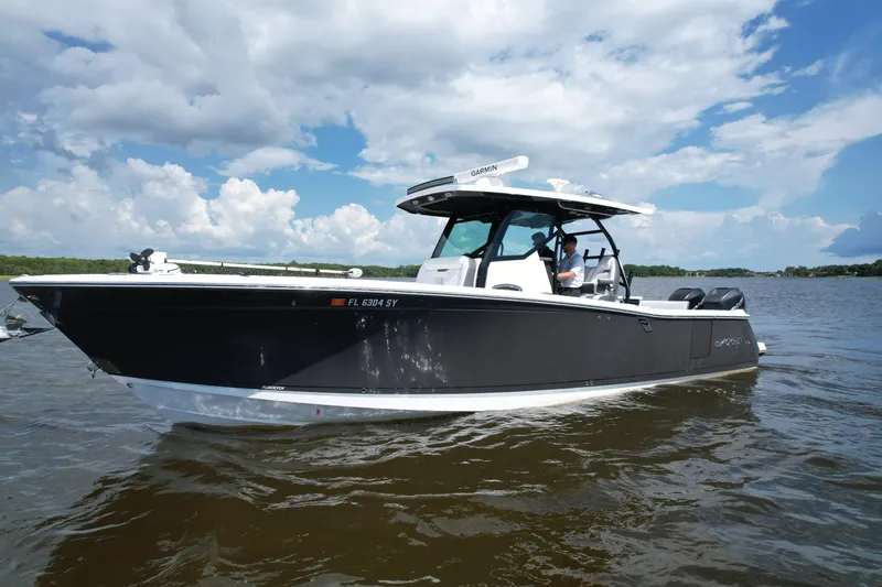 Slide: The Image of 2021 Blackfin 332 CC boat cruising on a calm lake under a partly cloudy sky. - 17