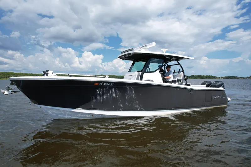 Slide: The Image of 2021 Blackfin 332 CC boat cruising on a calm lake under a partly cloudy sky. - 18
