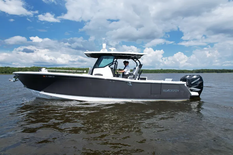 Slide: The Image of 2021 Blackfin 332 CC boat cruising on a calm lake under a partly cloudy sky. - 19