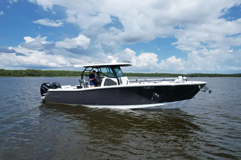 Slide: The Image of 2021 Blackfin 332 CC boat cruising on a calm lake under a partly cloudy sky. - 2