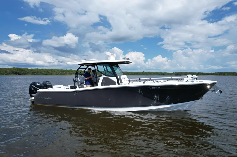 Slide: The Image of 2021 Blackfin 332 CC boat cruising on a calm lake under a partly cloudy sky. - 3