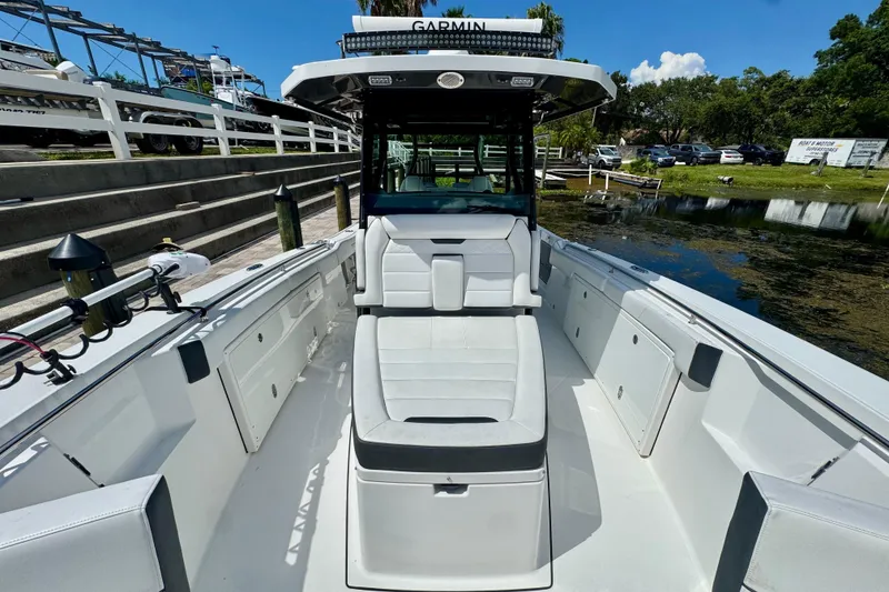 Slide: The Image of 2021 Blackfin 332 CC boat interior with seating and storage, docked by a calm waterway. - 31