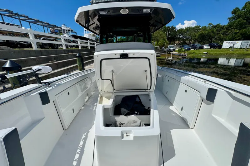 Slide: The Image of 2021 Blackfin 332 CC boat with open storage compartment, docked near a serene waterfront. - 32