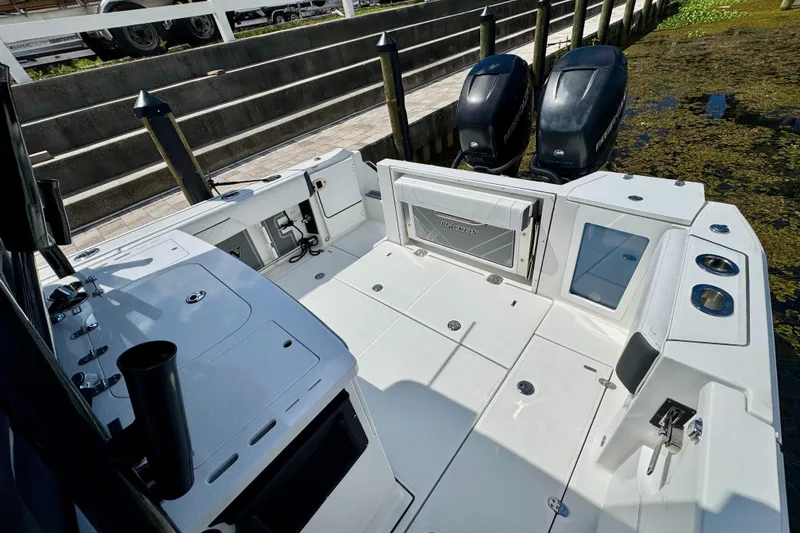 Slide: The Image of 2021 Blackfin 332 CC boat deck with dual engines, docked by a wooden pier. - 33