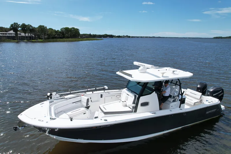 Slide: The Image of 2021 Blackfin 332 CC boat cruising on a serene lake under a clear blue sky. - 5