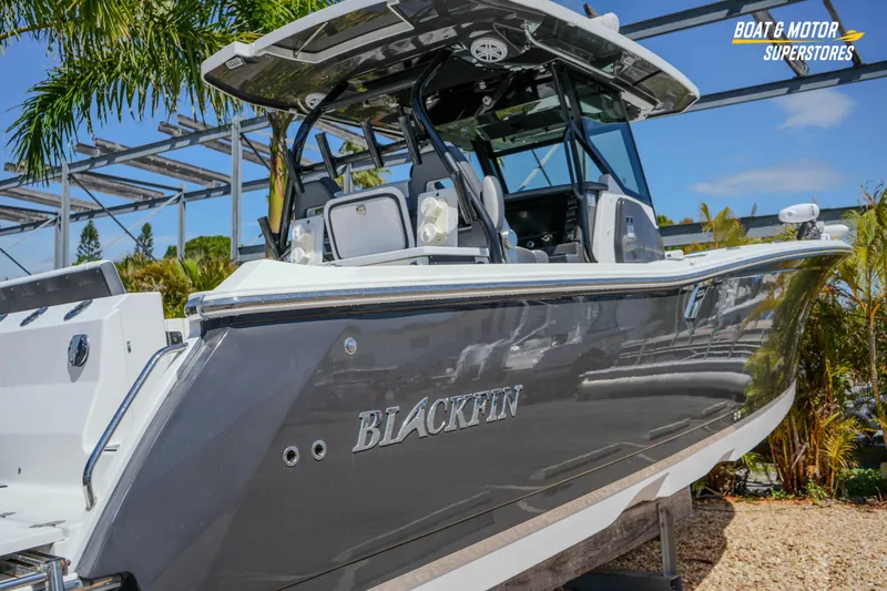 Slide: The Image of 2021 Blackfin 332 CC boat displayed outdoors with palm trees and blue sky. - 59
