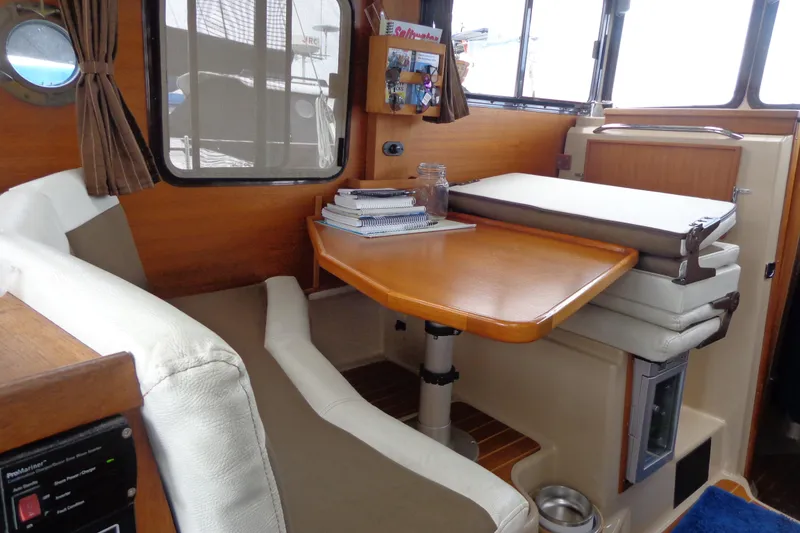Slide: The Image of 2011 Ranger Tugs R-29 Classic interior with wooden table, cushioned seating, and nautical decor. - 17