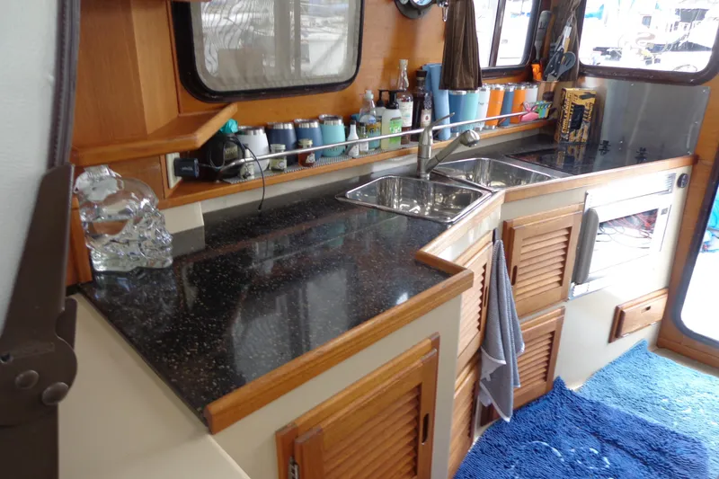 Slide: The Image of 2011 Ranger Tugs R-29 Classic interior kitchen with sink, countertop, and wooden cabinets. - 19
