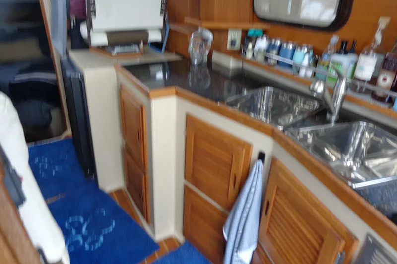 Slide: The Image of Interior of 2011 Ranger Tugs R-29 Classic, featuring a compact kitchen with wooden cabinetry. - 28