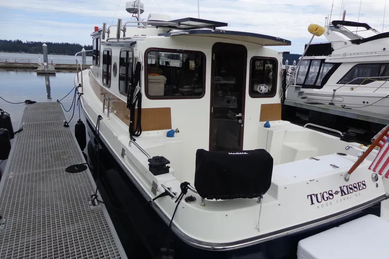 Slide: The Image of 2011 Ranger Tugs R-29 Classic boat docked, rear view with trailer, "Tugs & Kisses" name visible. - 4
