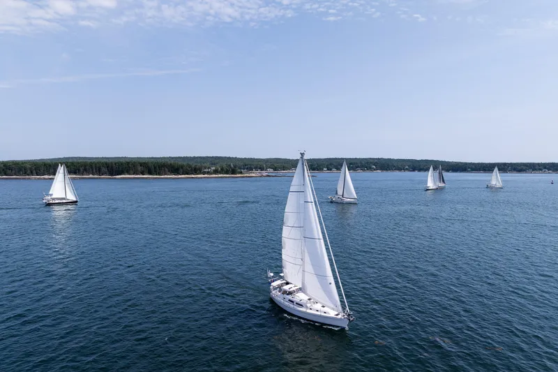 Slide: The Image of Sailboats on a serene lake, featuring a 2024 Outbound 46 model under clear skies. - 5