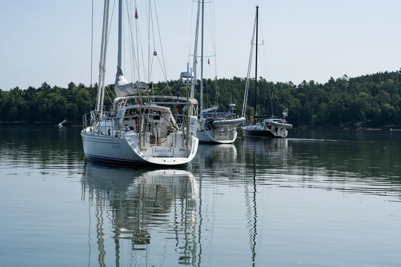 Slide: The Image of Sailboats, including a 2024 Outbound 46, anchored on a calm lake with forested shoreline. - 78