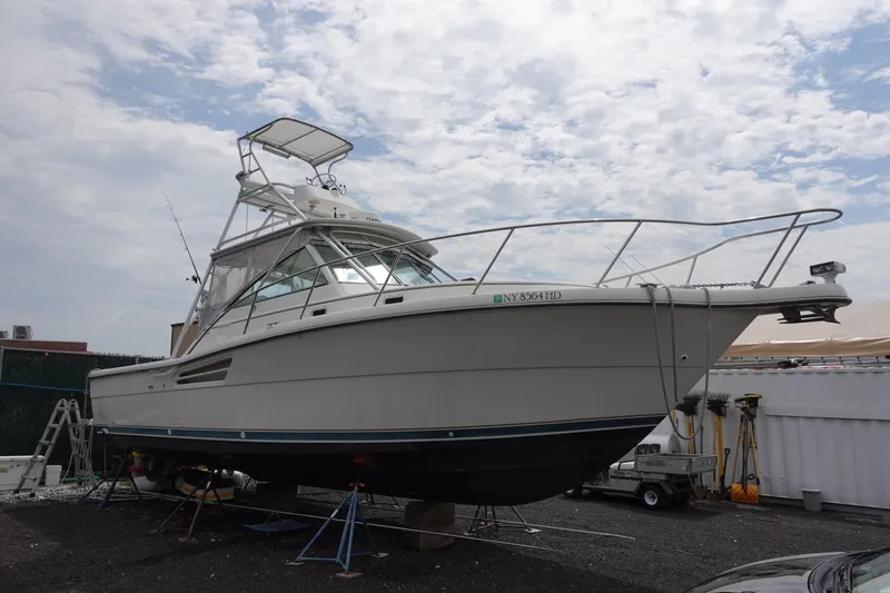 The Image of 1997 Pursuit 3400 Offshore boat on dry dock under cloudy sky. - 0