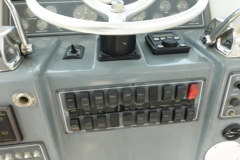 Slide: The Image of Control panel of a 1997 Pursuit 3400 Offshore boat with switches and steering wheel. - 11