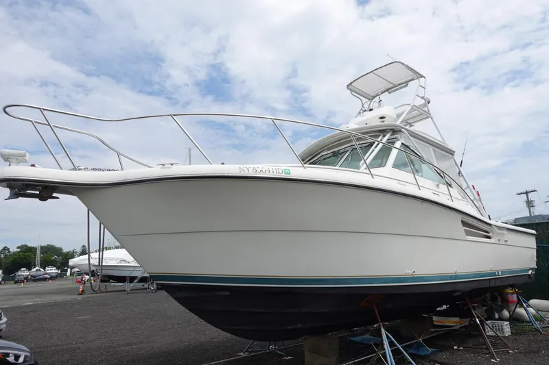 Slide: The Image of 1997 Pursuit 3400 Offshore boat on dry dock, white hull, clear sky background. - 2
