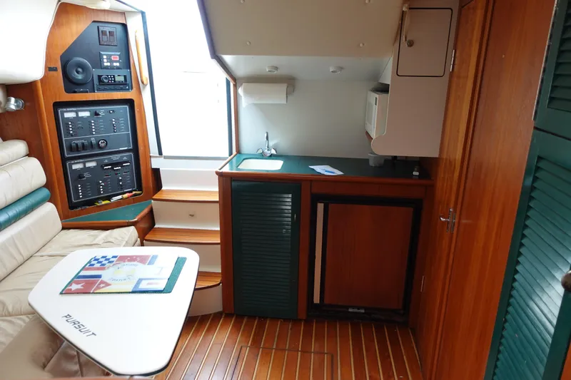 Slide: The Image of Interior of 1997 Pursuit 3400 Offshore boat with kitchenette and seating area. - 23