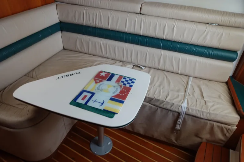 Slide: The Image of Interior of 1997 Pursuit 3400 Offshore boat with cushioned seating and nautical-themed table. - 24