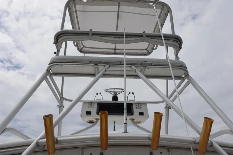 Slide: The Image of 1997 Pursuit 3400 Offshore boat tower with fishing rod holders against cloudy sky. - 4
