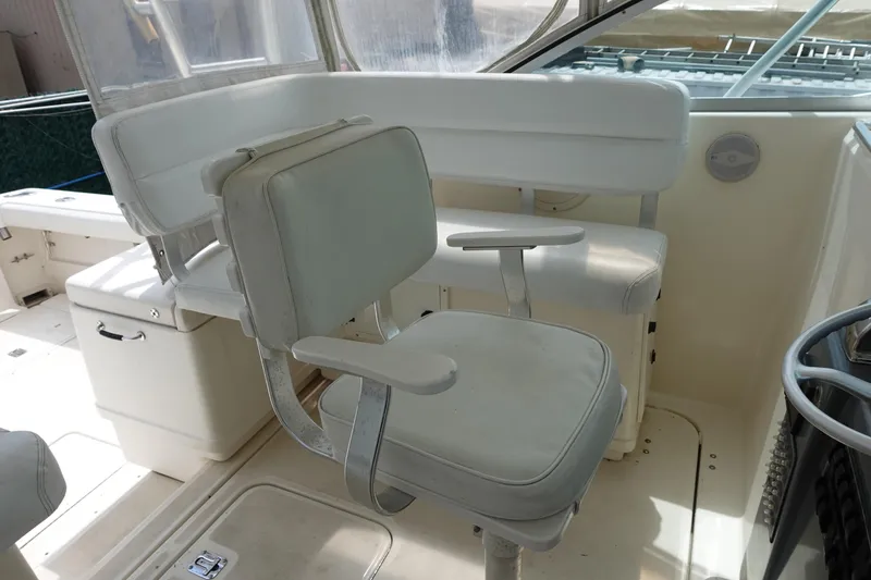 Slide: The Image of 1997 Pursuit 3400 Offshore boat interior with white seating and helm area. - 8