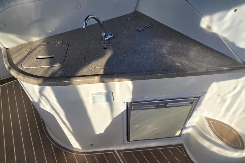 Slide: The Image of 2007 Rinker 320 Express Cruiser kitchenette with sink and mini fridge. - 13