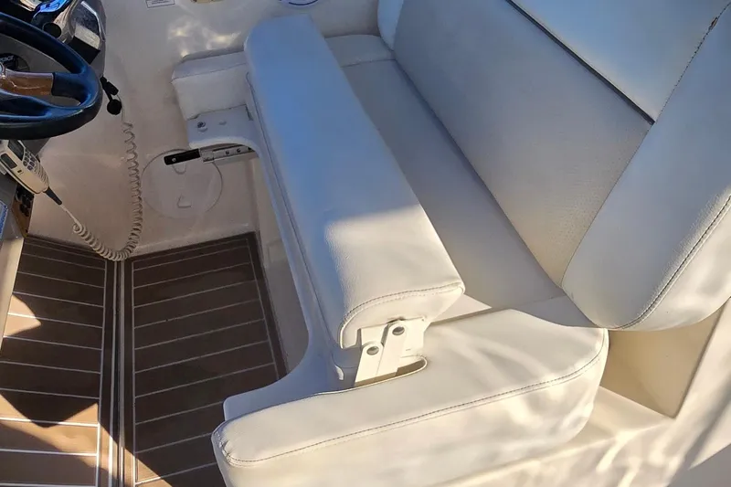 Slide: The Image of 2007 Rinker 320 Express Cruiser helm seat with white upholstery and wooden flooring. - 16