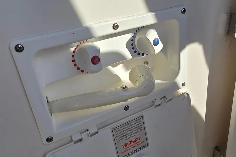 Slide: The Image of 2007 Rinker 320 Express Cruiser shower controls with temperature knobs and warning label. - 21