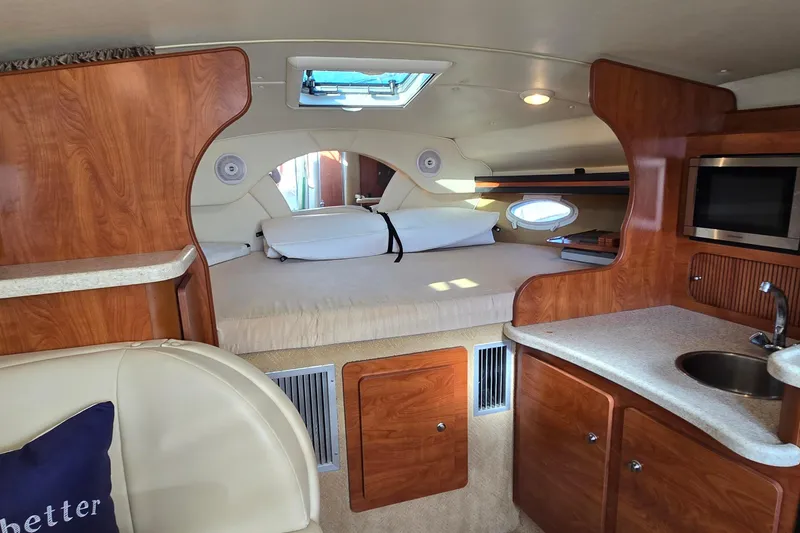 Slide: The Image of 2007 Rinker 320 Express Cruiser interior with bed, kitchenette, and wood finish. - 23